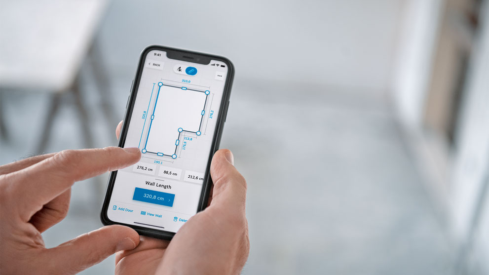 A hand holds a smartphone with a space planning app.