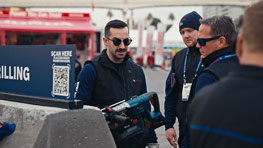 Trois hommes en vêtements de travail examinent un outil Bosch à l'extérieur.