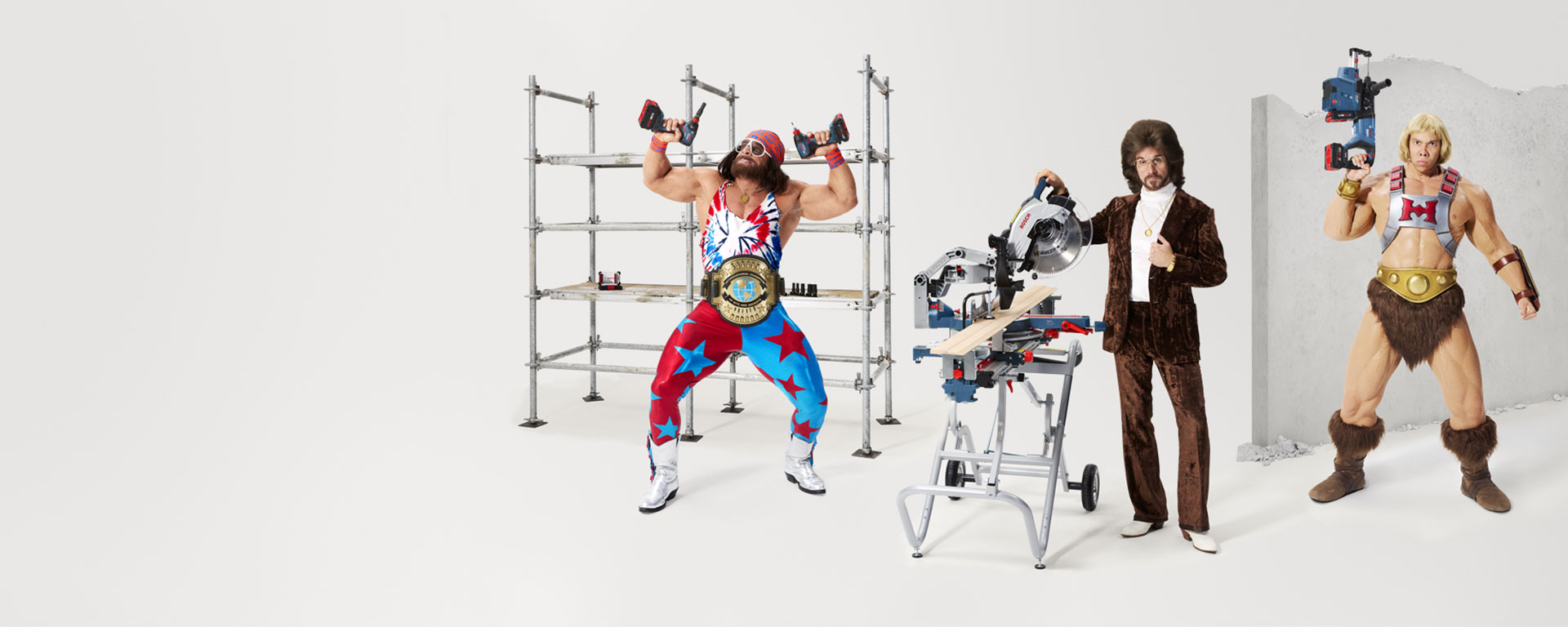 Hombre musculoso levanta pesas, rodeado de herramientas y decorados.