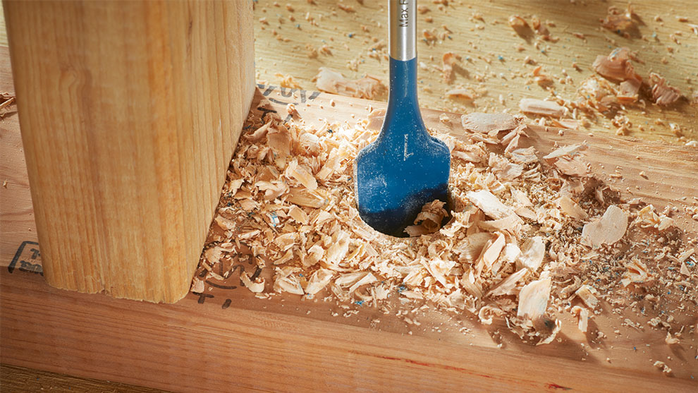 Une perceuse à bois bleue Bosch Professional est insérée dans un bloc de bois.