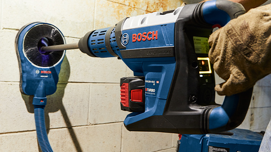 A blue Bosch Professional drill is being used on a wall.