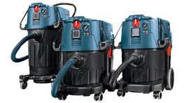 Three Bosch Professional vacuum cleaners in blue and black on wheels.