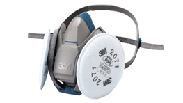 A 3M respirator with gray and white filter, lying on its side.