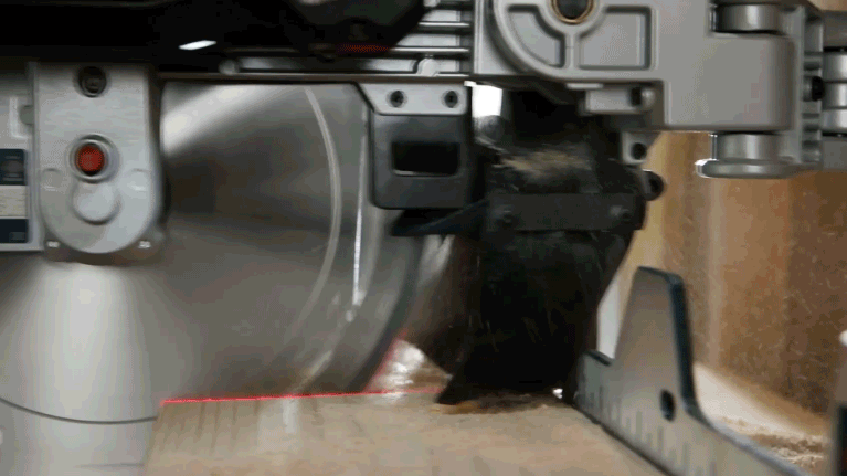 Una sierra circular Bosch Professional corta madera, el polvo vuela hacia arriba.