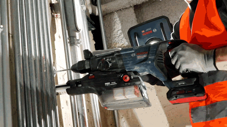 A Bosch Professional cordless hammer drill is being used on a wall.