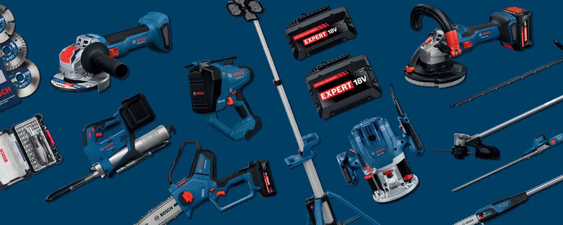 Several blue Bosch Professional tools are lying on a dark blue background. These include a cordless drill, a sander, a circular saw, and various batteries. The devices are arranged in different positions to showcase the variety of the product line.