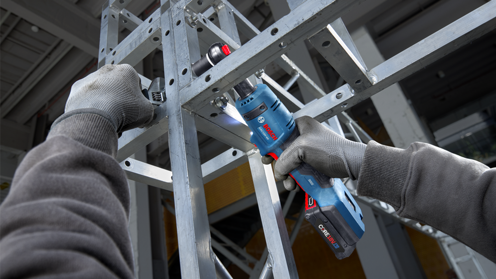 A Bosch Professional cordless drill is being used on a steel frame.