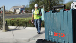 A Bosch toolbox is on the floor, a worker walks by.