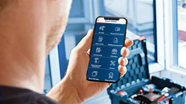 Man holds smartphone with Bosch Professional app in front of toolbox.