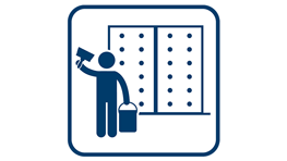 A person is painting a wall with a brush, next to them is a bucket.