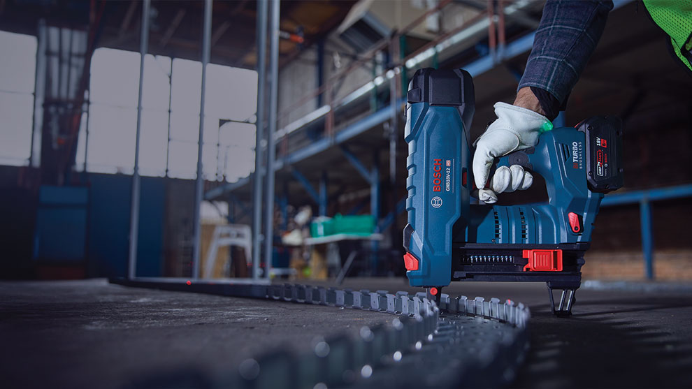 A Bosch Professional cordless nailer is held on the floor.