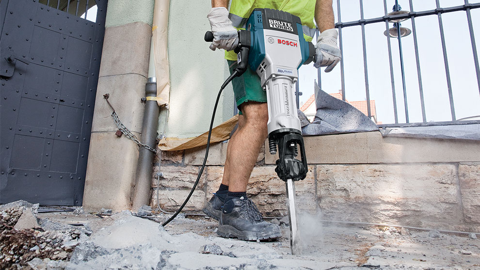A man is working the ground with a Bosch Brute Turbo demolition hammer.