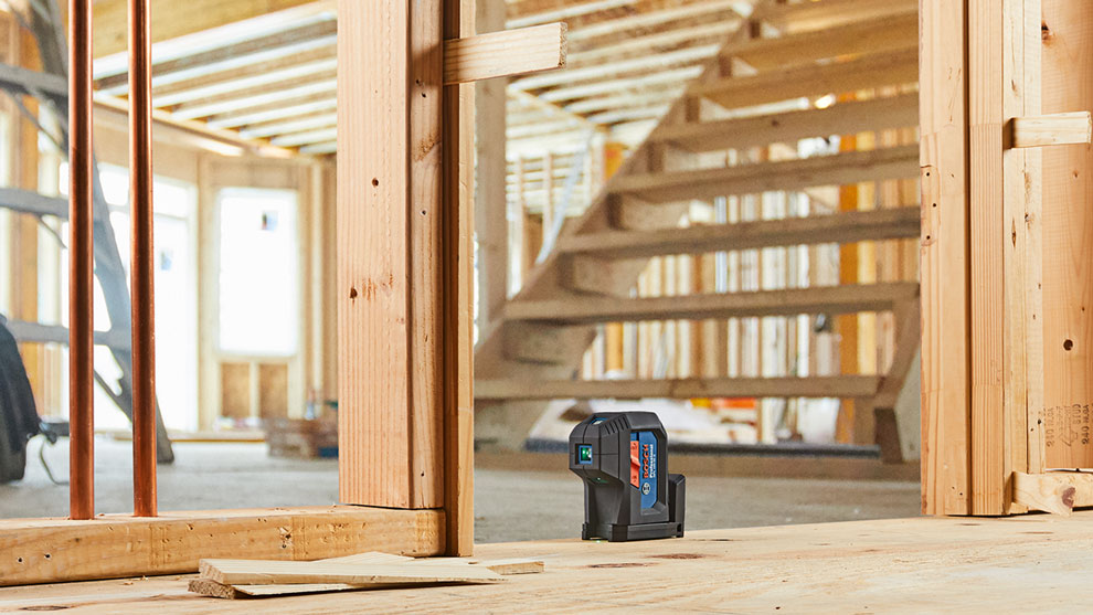 Bosch Professional Laser Level is standing on a wooden floor at a construction site.