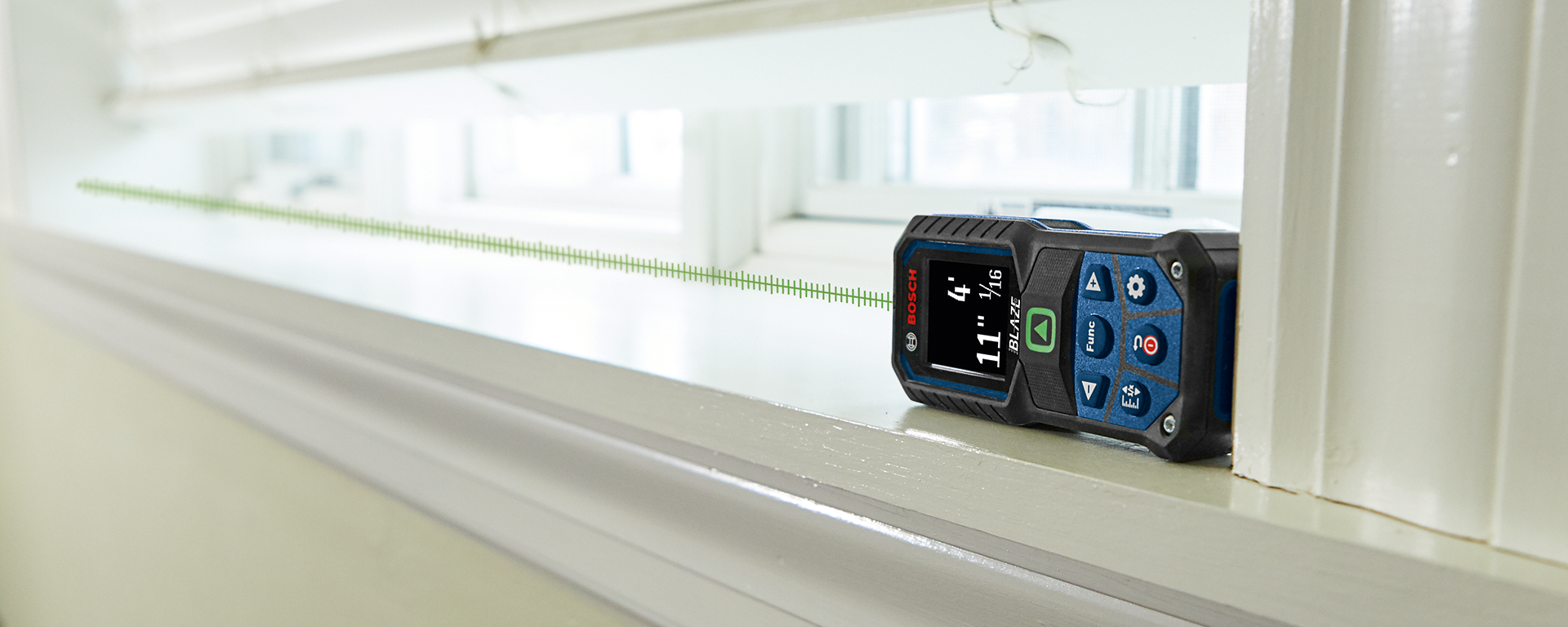 A Bosch Professional laser distance measurer is lying on a windowsill.