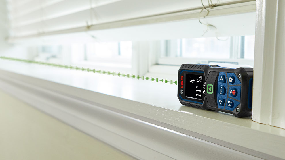 A Bosch Professional laser distance measurer is lying on a windowsill.