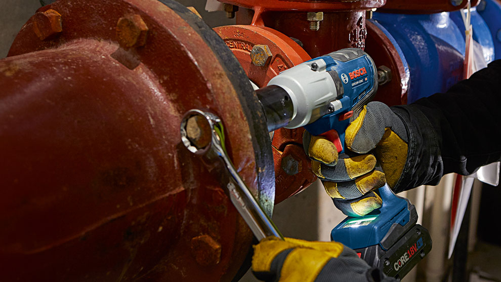 A Bosch Professional cordless screwdriver is used on a red pipe.